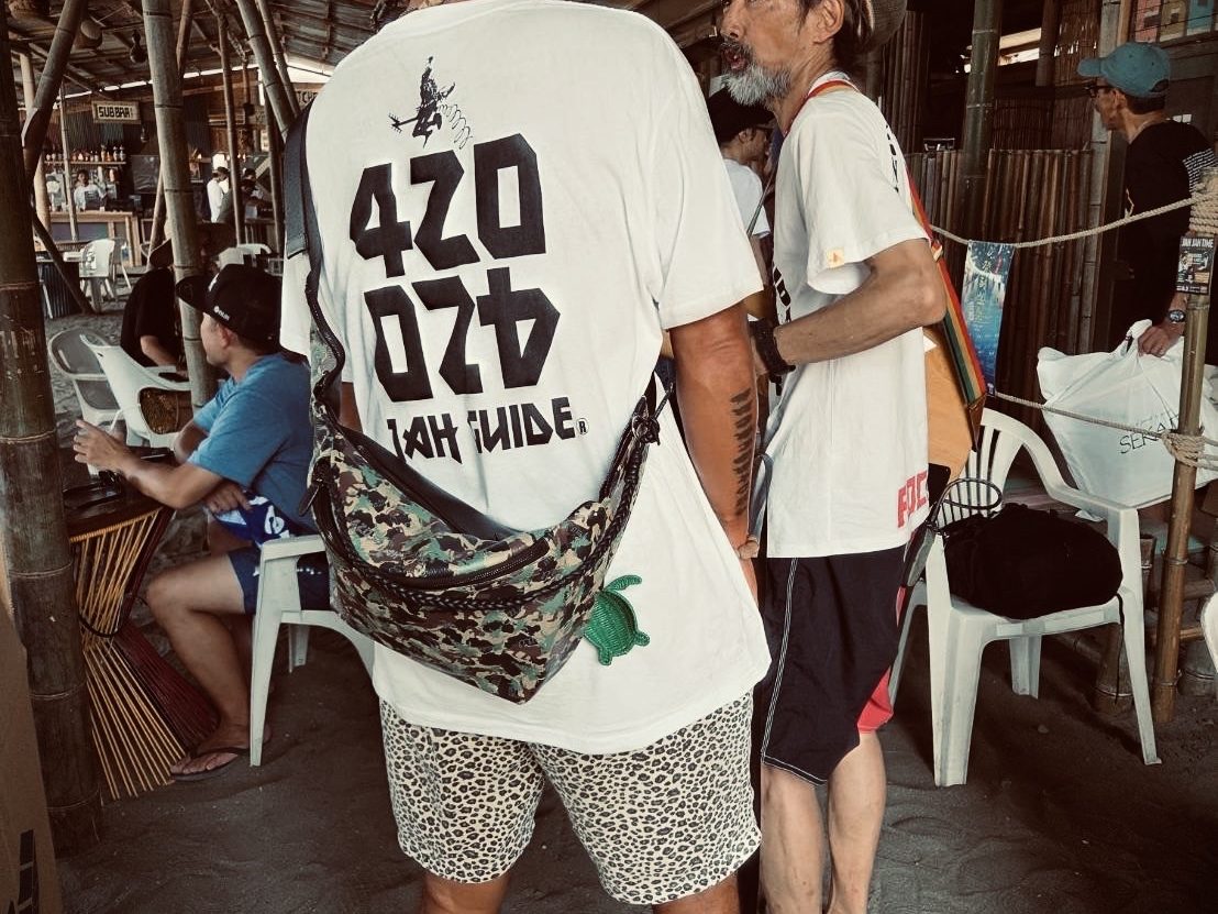 Bangkok — the JAH GUIDE logo across the back of a tee, in a beachside shack